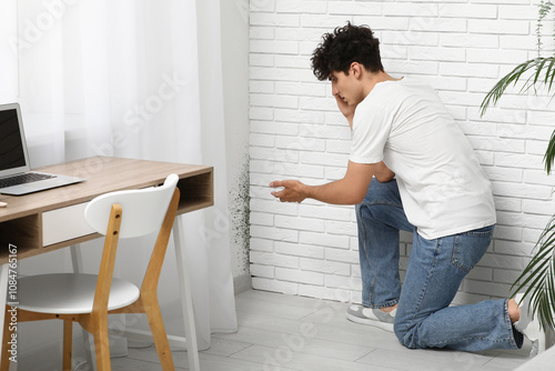 Young man with mold in corner at office