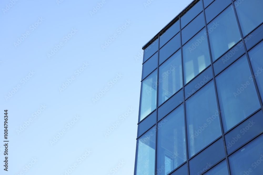 Exterior of modern building with many windows against light blue sky, low angle view. Space for text Exterior of modern building with many windows against light blue sky, low angle view. Space for text