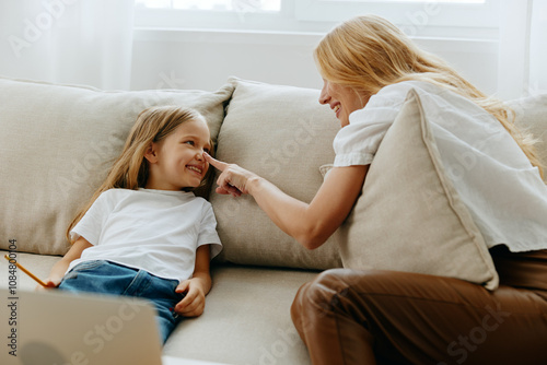 Fényképezés Mother and daughter bonding over educational content on a laptop while sitting o