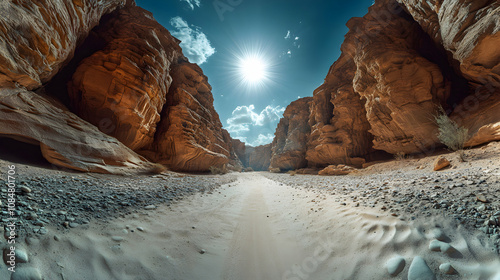 Sunlit Canyon: A Desert's Sandy Path Through Ancient,  Towering Sandstone Cliffs Under a Bright Sky