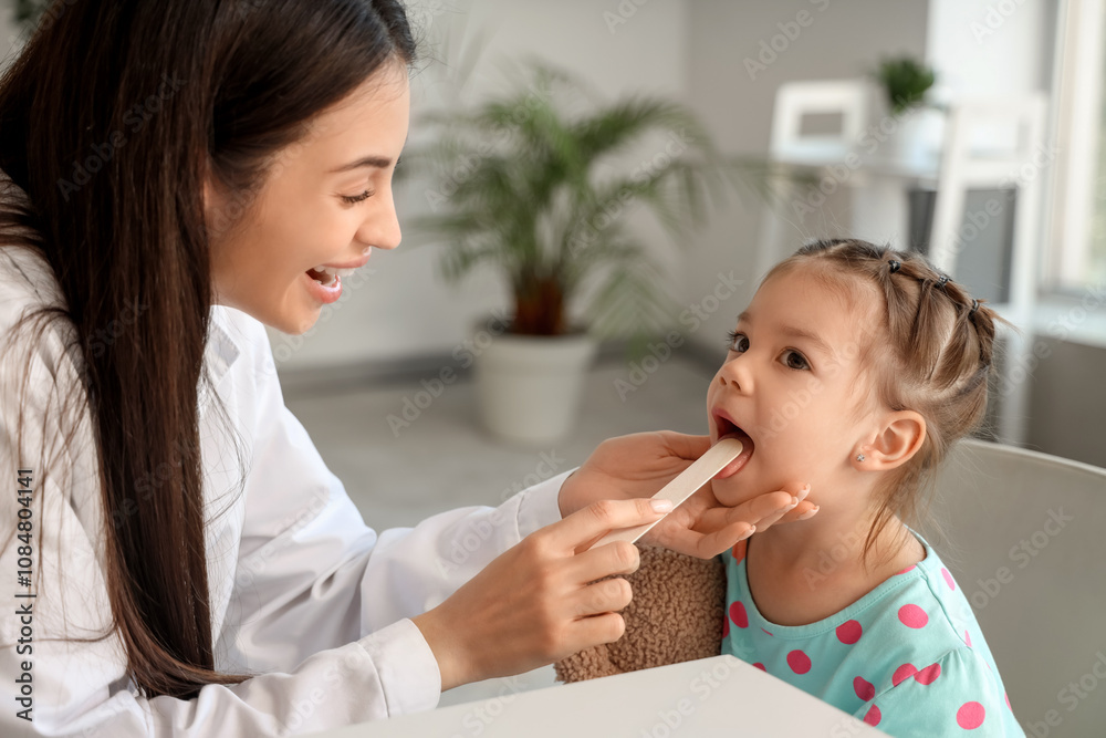 Female pediatrician checking little girl's throat in clinic Female pediatrician checking little girl's throat in clinic