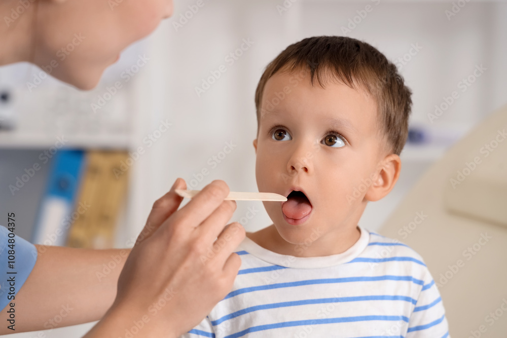 Female pediatrician checking little boy's throat in clinic, closeup Female pediatrician checking little boy's throat in clinic, closeup