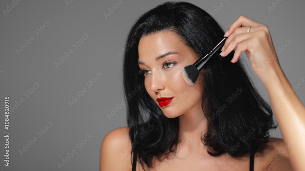 Close-up of a glamorous woman with striking red lips using a makeup brush, emphasizing flawless skin and beauty routines. Ideal for cosmetics, fashion editorials, and skincare promotions, highlighting Close-up of a glamorous woman with striking red lips using a makeup brush, emphasizing flawless skin and beauty routines. Ideal for cosmetics, fashion editorials, and skincare promotions, highlighting