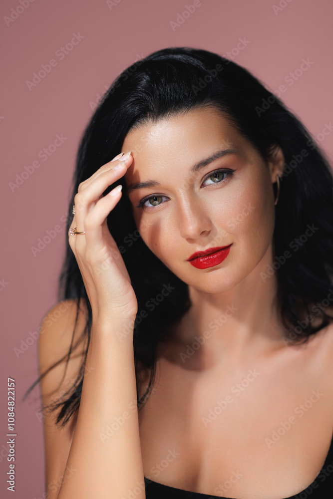 Fototapeta premium Close-up portrait of a glamorous woman with green eyes and bold red lips, set against a pink background. Ideal for beauty, fashion, and skincare promotions, high-quality advertisements, and editorial