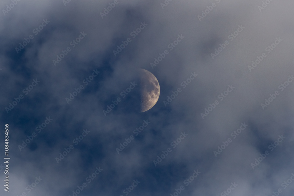 The moon in the dark blue sky with white clouds, closeup The moon in the dark blue sky with white clouds, closeup