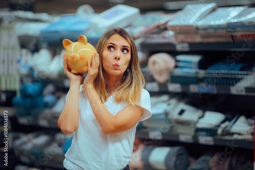 Woman Holding a Piggy Bank in a Supermarket During Sale Season. Cheerful shopper bargain hunting for inexpensive offers 