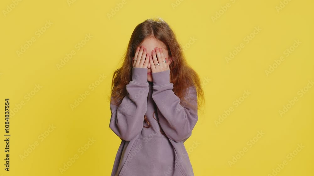 Curious young preteen child girl kid closing eyes with hand and spying through fingers, hiding, peeping, exploring way, seeking something in distance. Teenager children isolated on yellow background Curious young preteen child girl kid closing eyes with hand and spying through fingers, hiding, peeping, exploring way, seeking something in distance. Teenager children isolated on yellow background