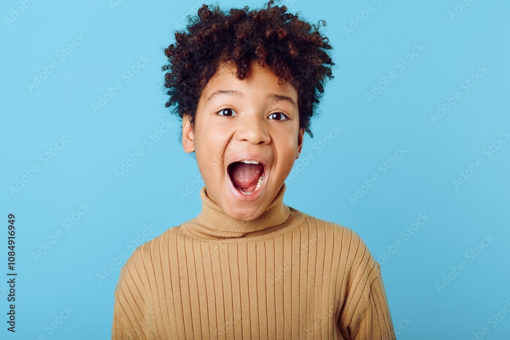 Surprised young african american boy with a bright expression and open mouth against a vibrant blue background Surprised young african american boy with a bright expression and open mouth against a vibrant blue background