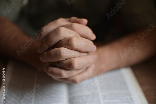 close up on the hands of an unrecognizable man reading the bible and praying. Concept of religiosity and mystery