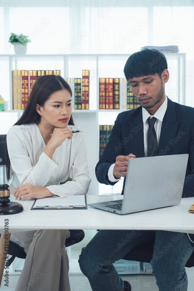 Lawyers Collaborating on Case: A serious legal professional couple working together on a laptop in their office. Lawyers Collaborating on Case: A serious legal professional couple working together on a laptop in their office.