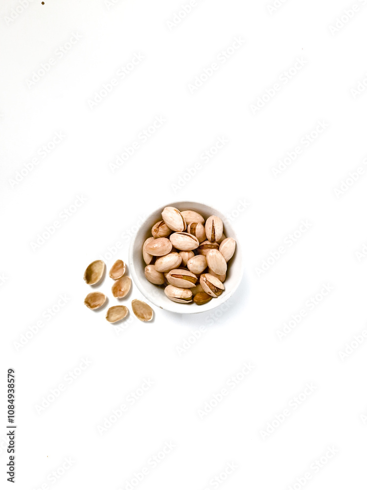 Pistachios are served in a white bowl with a shell around it Pistachios are served in a white bowl with a shell around it
