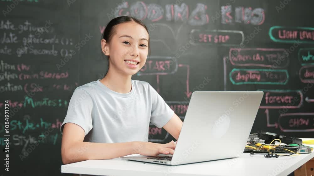 Smart girl programming system by using laptop at blackboard. high school student writing engineering code or prompt while looking at camera at STEM technology class. Creative education. Edification Smart girl programming system by using laptop at blackboard. high school student writing engineering code or prompt while looking at camera at STEM technology class. Creative education. Edification