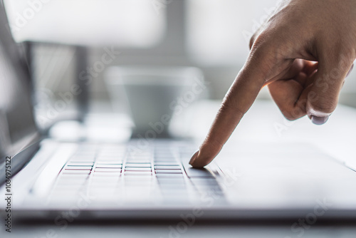 Against a blurred office scene, the image details a woman's hands nimbly typing on a trendy laptop keyboard