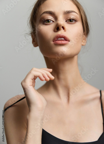 Graceful young woman posing confidently with soft lighting, showcasing natural beauty and elegance. Close-up portrait highlights facial features and delicate posture.