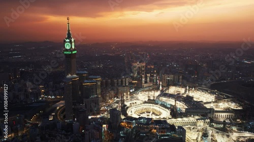 Aerial view of the illuminated Grand Mosque and Abraj Al-Bait Clock Tower in Mecca at dusk, showcasing the holy city’s vibrant atmosphere as night falls