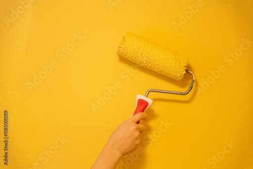 Roller Brush Painting, Worker painting on surface wall Painting apartment, renovating with yellow color paint.