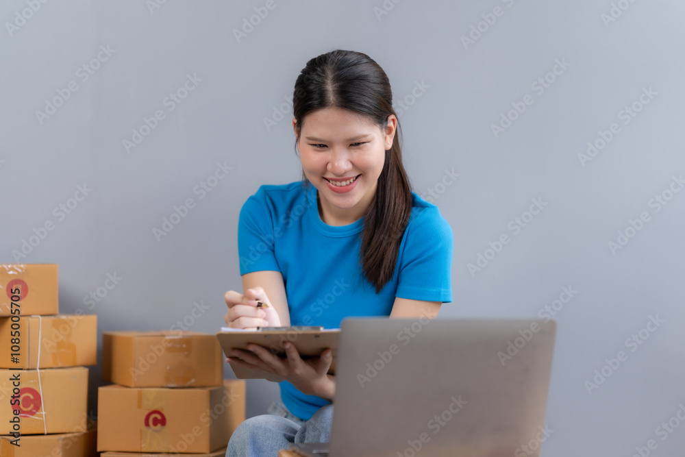 Smiling Business Owner: A young woman, radiating positivity and energy, manages her online business amidst a stack of shipping boxes. Smiling Business Owner: A young woman, radiating positivity and energy, manages her online business amidst a stack of shipping boxes.