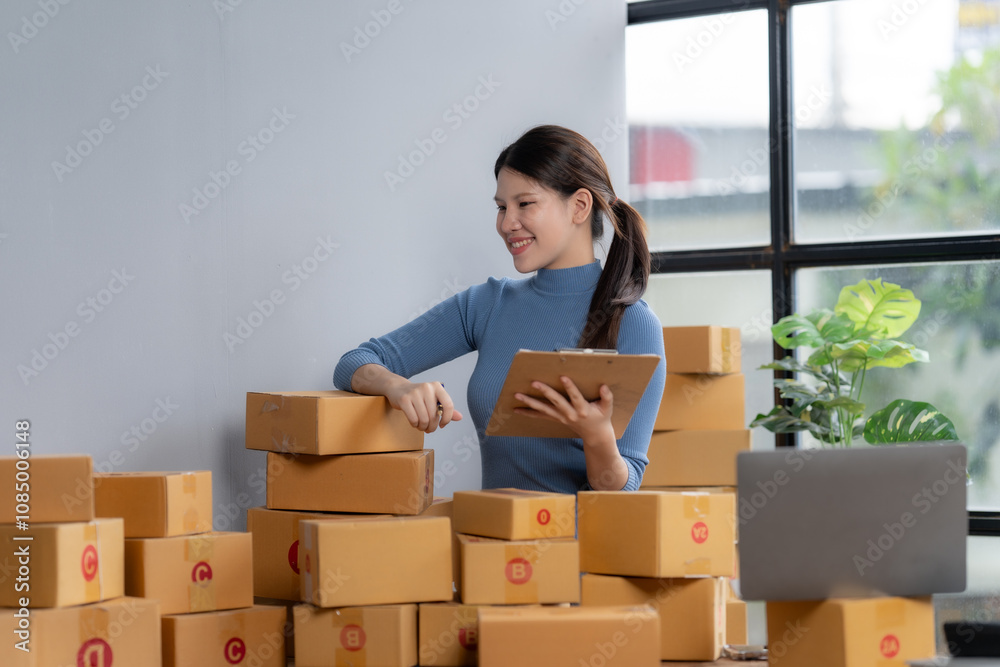 Smiling woman checking orders amidst cardboard boxes Smiling woman checking orders amidst cardboard boxes
