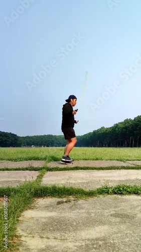 A boy with a hoodie is doing jump rope in the park photo