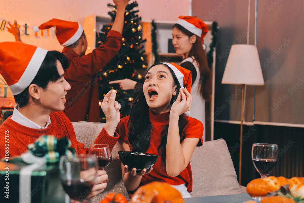 Group of young Asian man and women as friends having fun at a New Year's celebration, holding gift boxes standing by Christmas tree decoration, midnight countdown Party at home with holiday season. Group of young Asian man and women as friends having fun at a New Year's celebration, holding gift boxes standing by Christmas tree decoration, midnight countdown Party at home with holiday season.