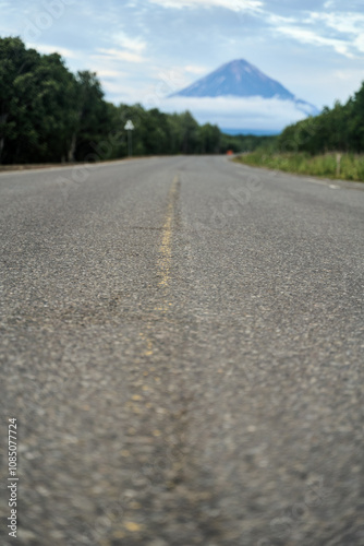 Wallpaper Mural A tranquil and serene road scene features a majestic mountain rising beautifully underneath a cloudy sky Torontodigital.ca