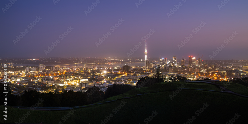 Obraz premium Sky Tower and Auckland Harbour Bridge at dawn. Volcanic crater in the foreground. Mt Eden summit. Auckland.