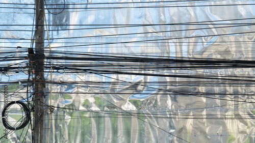 A complex network of electrical wires against a reflective surface, showcasing the intricacies of urban infrastructure.