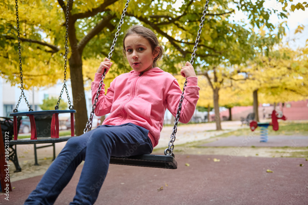 Young girl swinging joyfully in a vibrant autumn park setting Young girl swinging joyfully in a vibrant autumn park setting