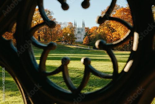 View of the autumn trees through the Gothic ornament of the ancient well, the Gothic church in the park. Autumn in a public park