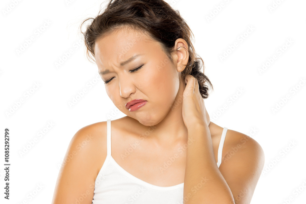 Asian woman with pain in the nech holding it with arm with painful expression on her face Asian woman with pain in the nech holding it with arm with painful expression on her face