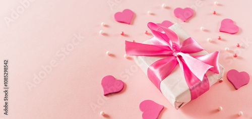 Pink hearts and gift box with ribbon on a light pink background