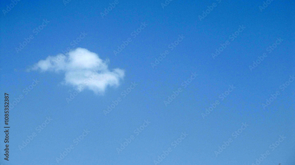 Clear blue sky with a single white cloud, creating a minimalistic natural view. Clear blue sky with a single white cloud, creating a minimalistic natural view.