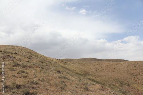 Dry hills and rugged terrain stretching across the landscape under a cloudy sky.