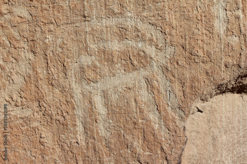 Fototapeta premium Large stone engravings on an ancient rock face in an isolated, rugged desert landscape.