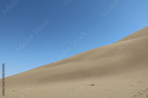Fototapeta Naklejka Na Ścianę i Meble -  Sand dunes with smooth textures under a clear sky, showcasing desert's elegance.