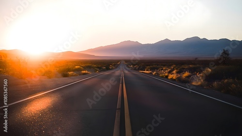 An idyllic and scenic path winds toward the distant horizon, enveloped in a breathtaking sunset as the bright sun fades behind the distant peaks, casting a golden glow.