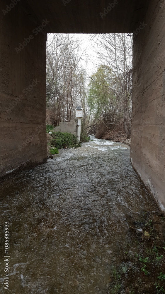 Obraz premium A pathway through an old rustic structure, surrounded by textured walls, leading to a shaded, mysterious interior, evoking timelessness and tradition.