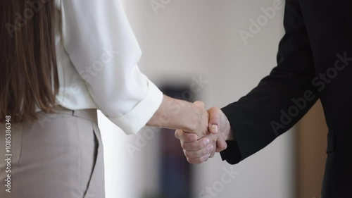 Strong handshake between professionals in corporate environment as symbol of trust and partnership. Close up of handshake between two professionals against background of blurred modern office interior