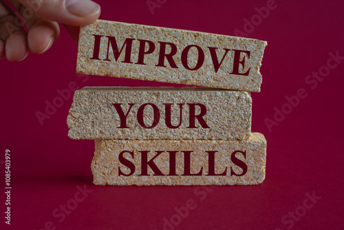 Improve your skills symbol. Concept word Improve your skills written on the brick blocks. Beautiful red background. Businessman hand.