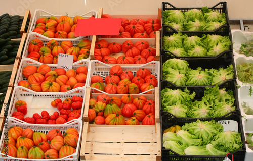 Fototapeta Naklejka Na Ścianę i Meble -  fruit and vegetable stall at a farme s market with many crates of fresh tomatoes, green lettuce