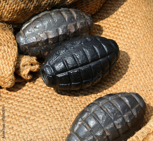 three black grenades or hand grenades on a jute background used during the war photo