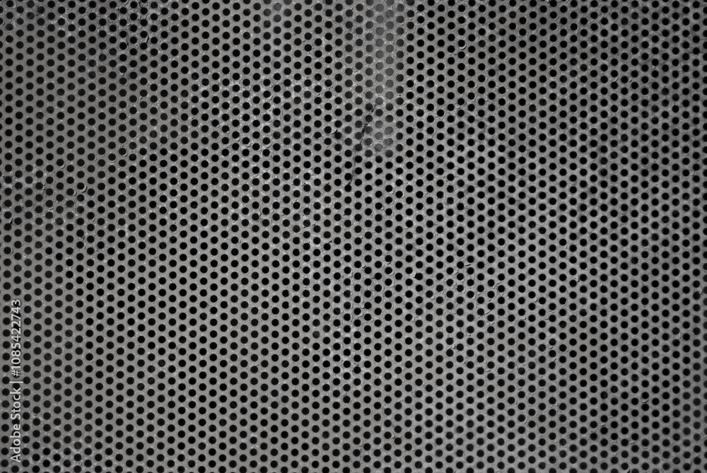 The photo shows an old perforated sheet of grey metal The photo shows an old perforated sheet of grey metal