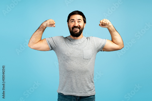 Strong man showing muscles and smiling on blue background photo