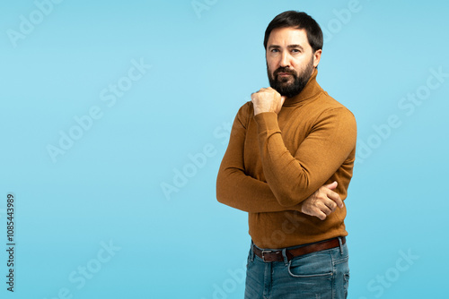 Pensive man touching chin on blue background,