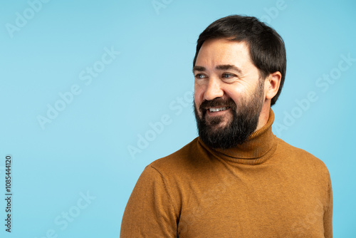 Smiling bearded man looking away on blue background