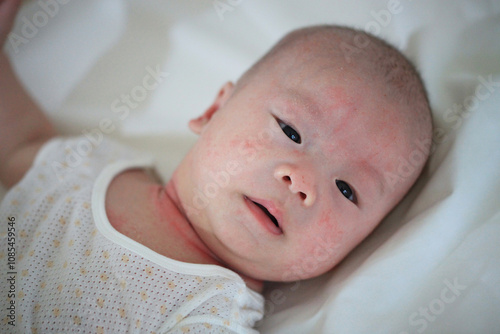A newborn baby lying on a soft white blanket, showing delicate features and curious expression in a serene setting