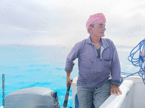 Old Sailor in the Sea Riding and Sailing with his Boat An old sailor with a white with a white mustache who is wearing a Bedouin Scarf on his head