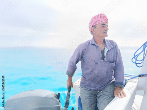 Old Sailor in the Sea Riding and Sailing with his Boat An old sailor with a white with a white mustache who is wearing a Bedouin Scarf on his head