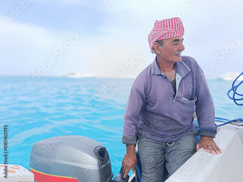 Old Sailor in the Sea Riding and Sailing with his Boat An old sailor with a white with a white mustache who is wearing a Bedouin Scarf on his head