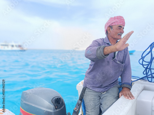 Old Sailor in the Sea Riding and Sailing with his Boat An old sailor with a white with a white mustache who is wearing a Bedouin Scarf on his head